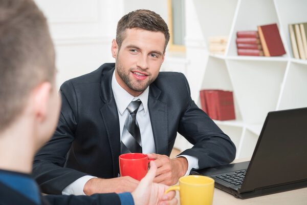 Two businessmen in suits having a coffee-break