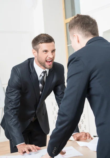 Two angry businessmen standing near table — Stock Photo, Image