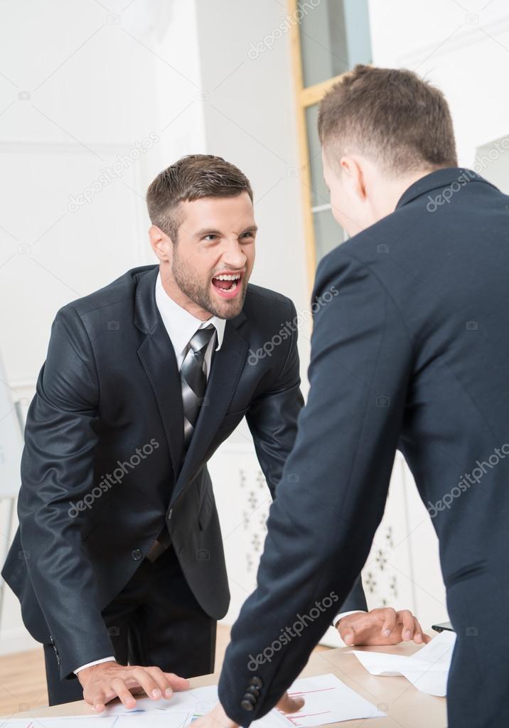 Two angry businessmen standing near table
