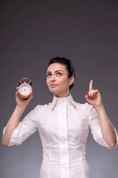 Portrait of pretty girl holding an alarm clock in her hand showi — Stock Photo, Image