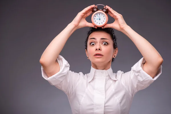 Portrait of pretty girl holding an alarm clock in her hand showi — Stock Photo, Image