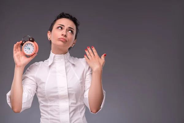 Chica pensando en algo mientras sostiene un reloj despertador — Foto de Stock