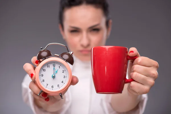 Girl holding an alarm clock and a red cup — Stock Photo, Image