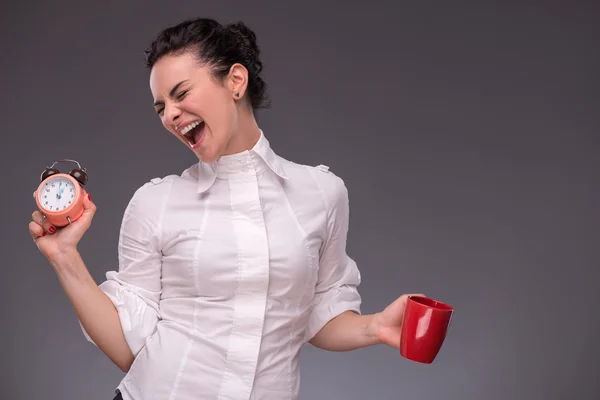 Счастливая девушка с будильником и красной чашкой — стоковое фото