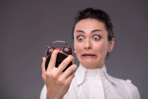 Girl with surprised face holding an alarm clock — Stock Photo, Image