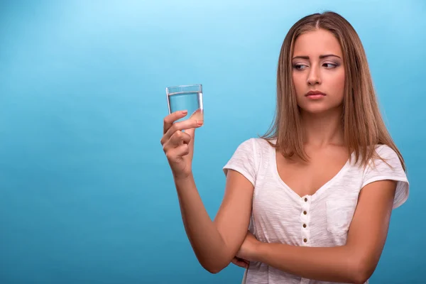 Девушка с подозрением смотрит на стакан с чистой водой — стоковое фото