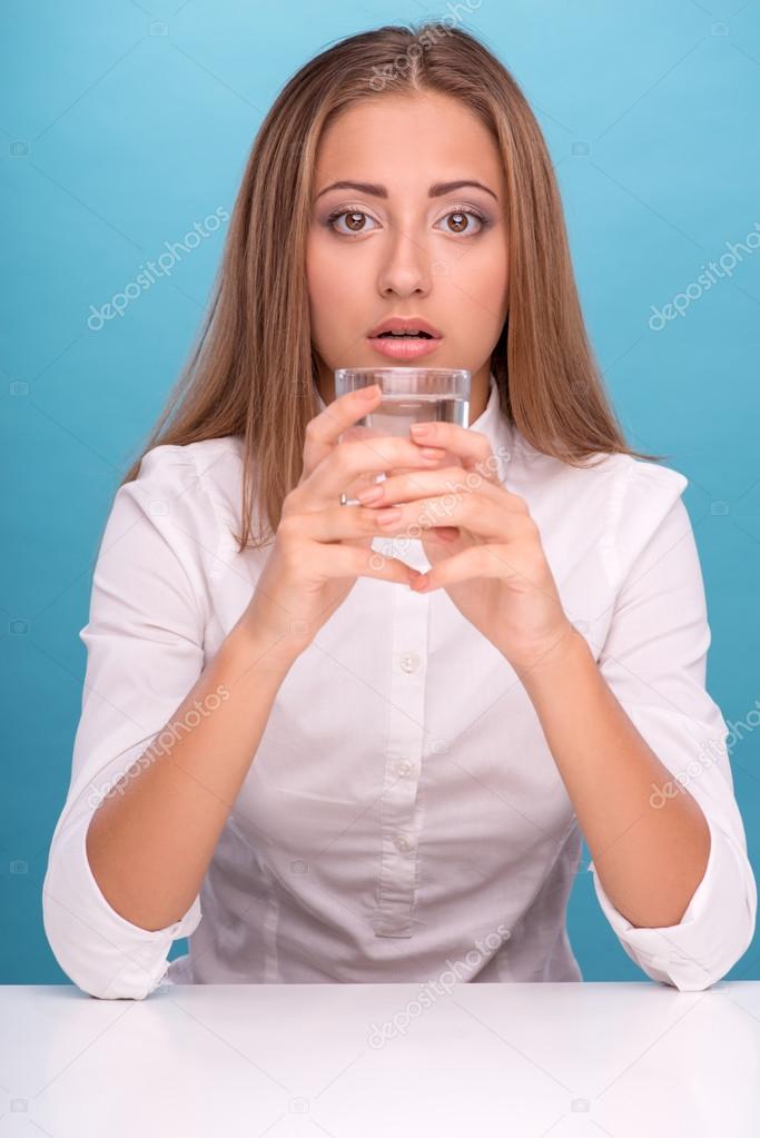 Portrait of young beautiful girl holding a glass with clean wate