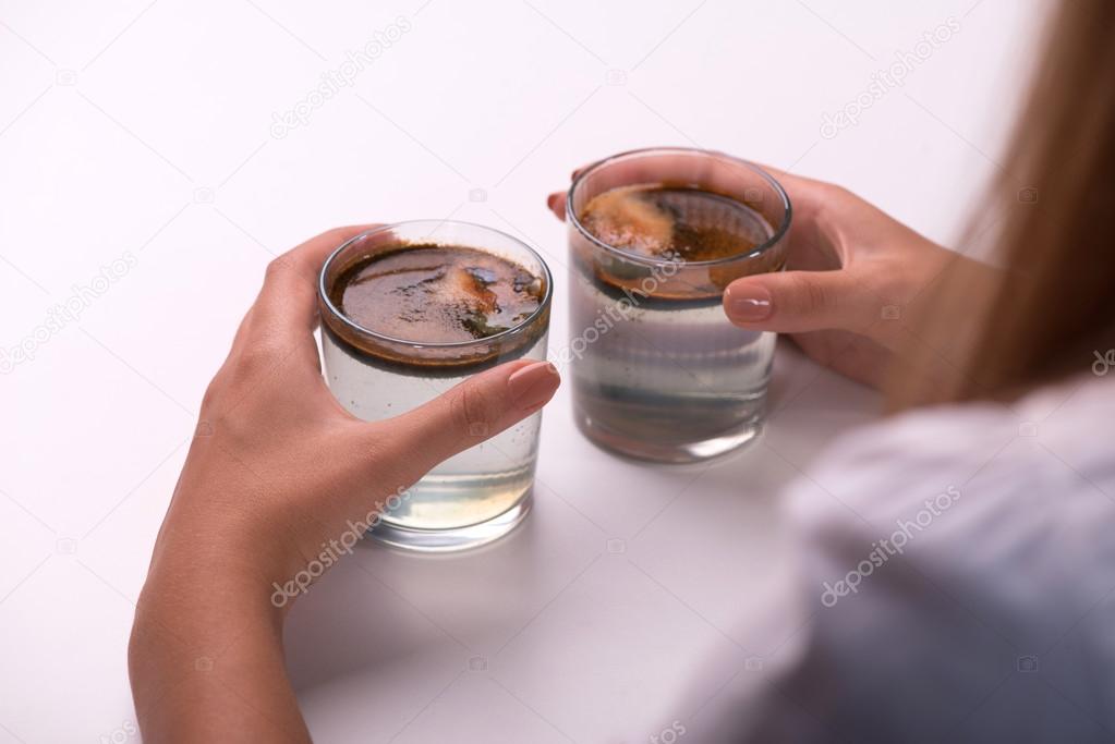 Young girl testing the quality of water in glasses