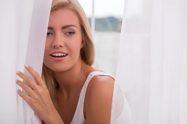 Girl looking out curtain — Stock Photo, Image