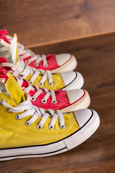 Sapatos de ginástica jovens multicoloridos no chão — Fotografia de Stock