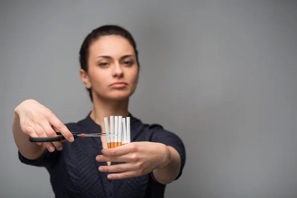 Mulher corta cigarros com tesoura — Fotografia de Stock