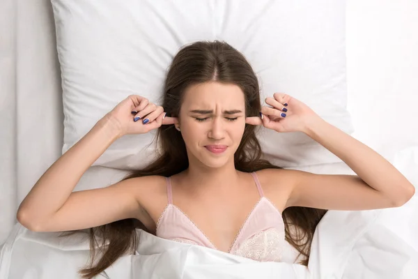 Beauty lying in the bed covering ears — Stock Photo, Image