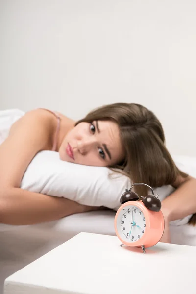 Beauté couché sur le lit avec une horloge — Photo