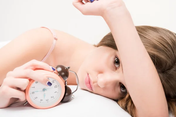 Beauty lying on the bed with clock — Stock Photo, Image