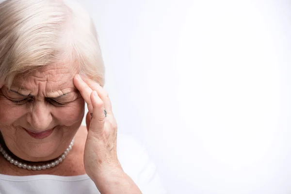 Oudere dame haar hoofd met vingers aan te raken — Stockfoto