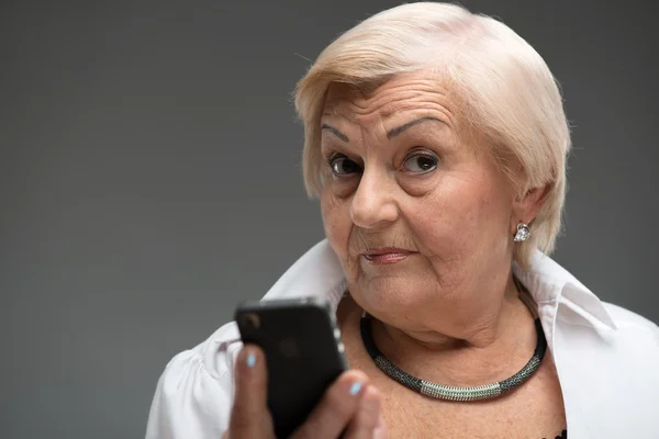 Femme âgée tenant un smartphone — Photo