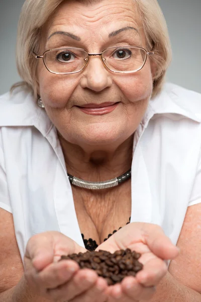 Mulher idosa segurando grãos de café — Fotografia de Stock