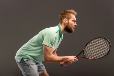 Genç adam tenis oynuyor.