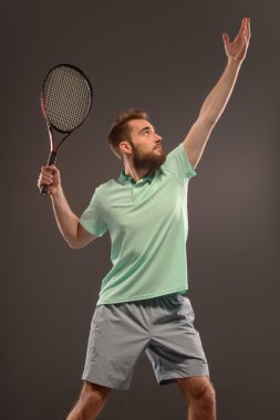 Genç adam tenis oynuyor.