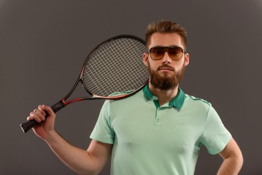 Genç adam tenis oynuyor.