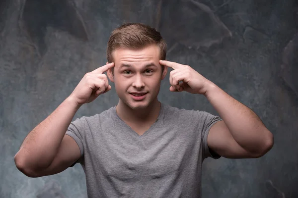 Jonge man met vingers op zijn tempels — Stockfoto