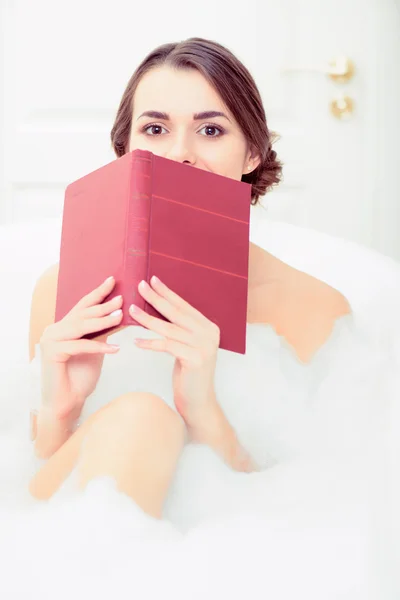 Красива молода жінка в ванній з книгою — стокове фото