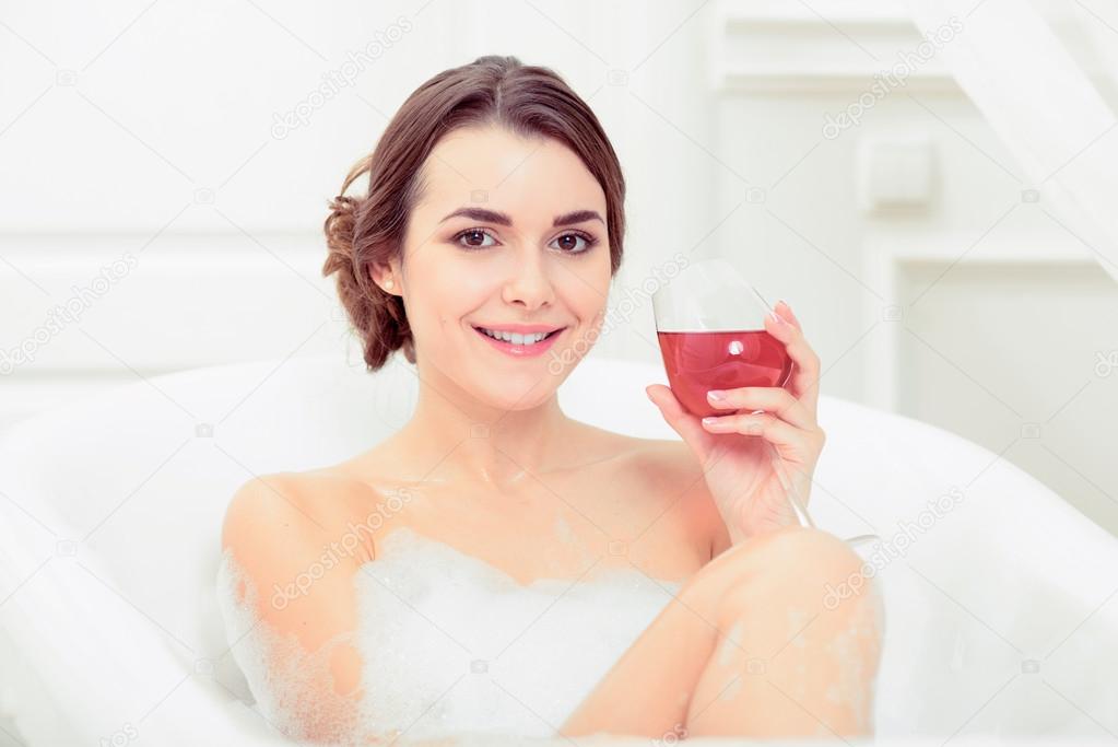 Woman in bath with a wine glass