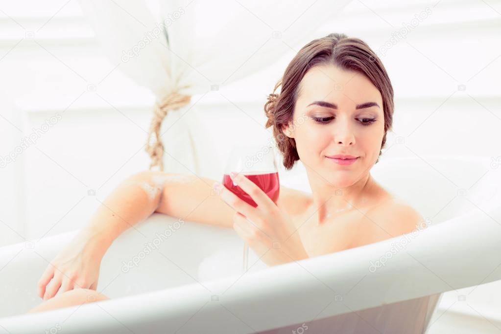 Woman in bath with a wine glass