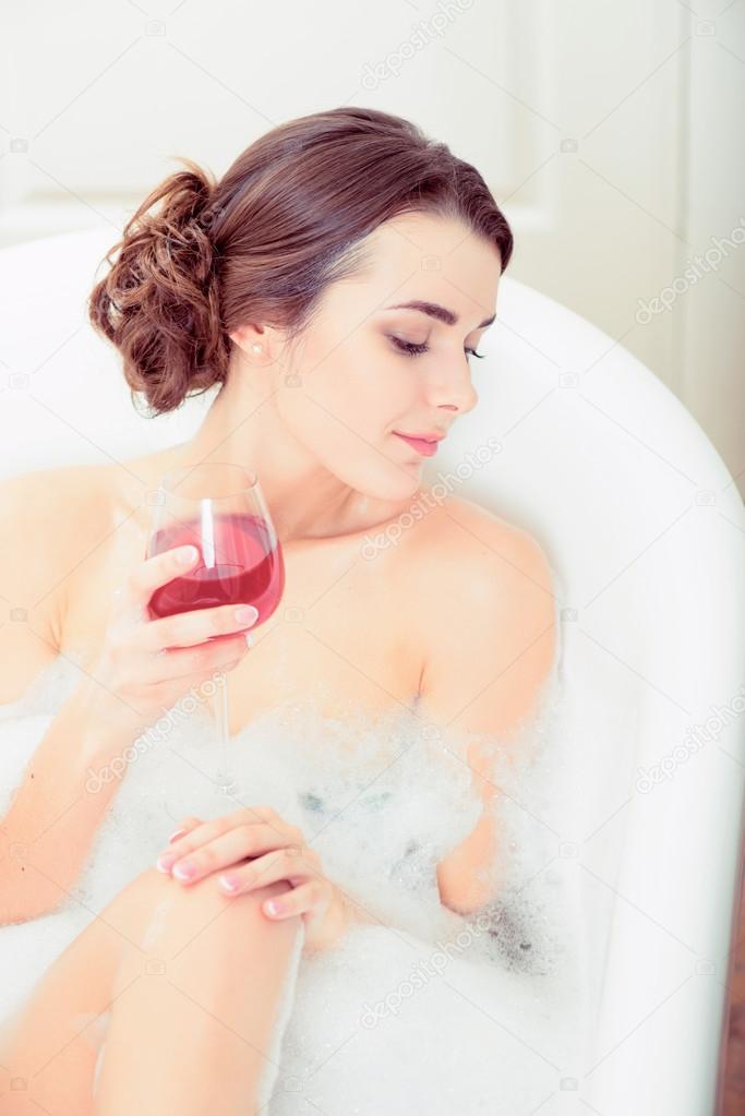 Young woman in bath with a wine glass