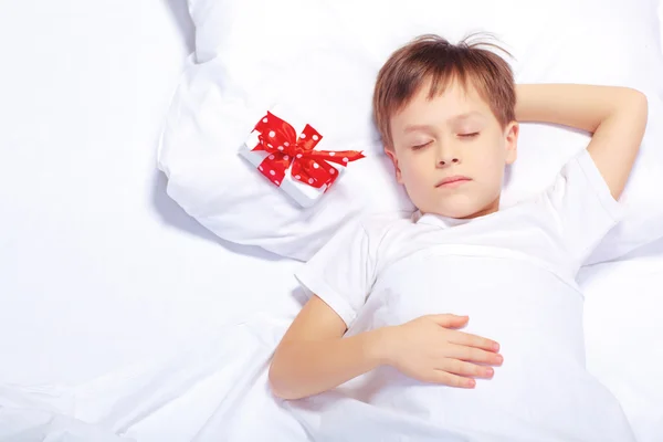 Portrait de petit garçon au lit avec un cadeau — Photo