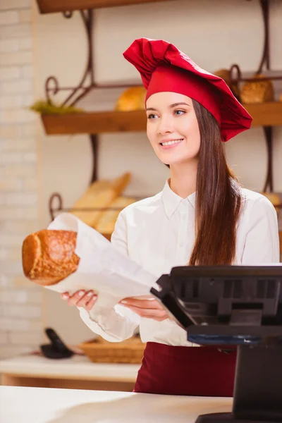 Mulher esticando um pacote de papel com pão — Fotografia de Stock