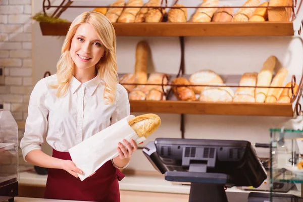 Baker sträcker ut ett papper paket med bröd — Stockfoto