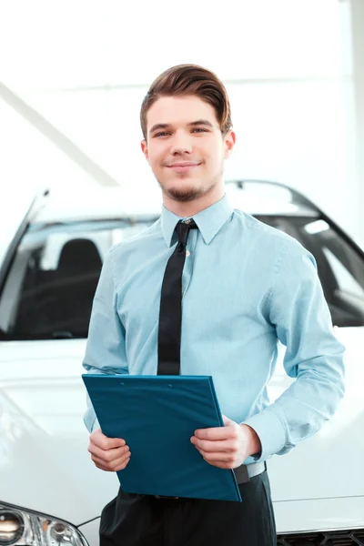 Car sales man in formalwear holding a clipboard — Stock Photo, Image