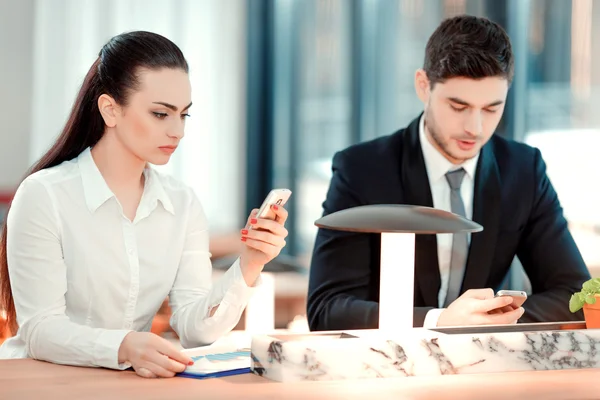 Empresarios mirando sus teléfonos móviles — Foto de Stock