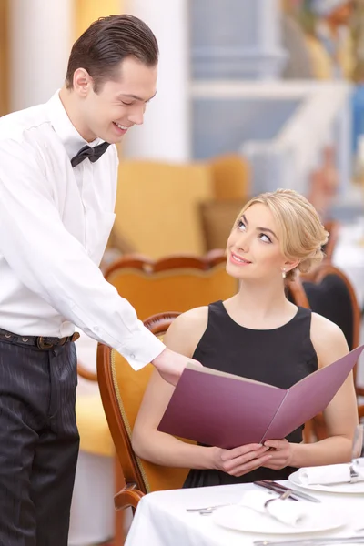 Woman looking waiter pointing at menu — Stock Photo, Image