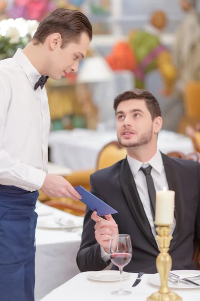Waiter giving a bill to his customer Stock Image