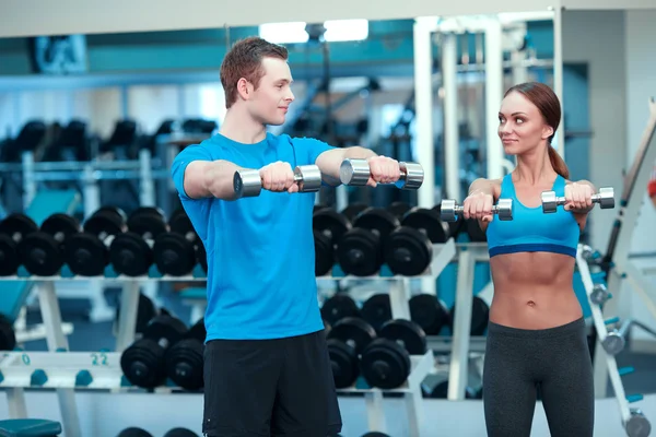 Beautiful girl in sports club with instructor — Stock Photo, Image