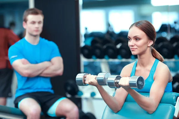 Beautiful girl in sports club with instructor — Stock Photo, Image