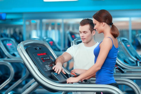 Hermosa chica en el club deportivo con instructor — Foto de Stock