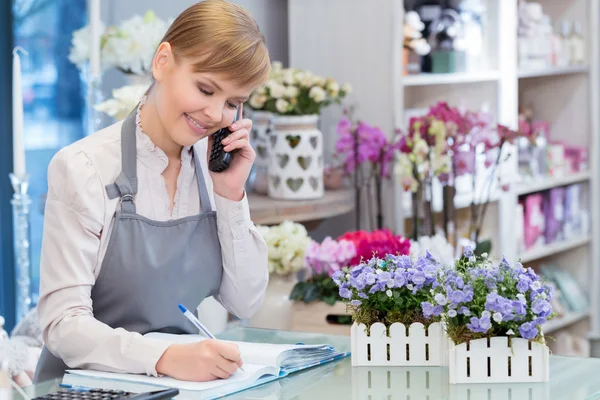 Florist prata via telefon och att göra anteckningar — Stockfoto