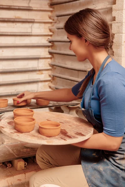 Woman puts clay pots on the shelf — Stock Photo, Image