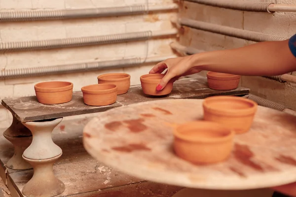 Woman puts clay pots on the shelf — Stock Photo, Image