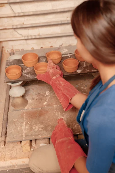 Woman puts clay pots on the shelf — Stock Photo, Image