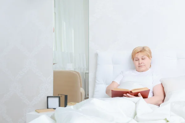 Mujer lee un libro en la cama — Foto de Stock