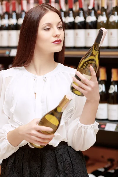 Vrouw houdt een fles wijn in de winkel — Stockfoto