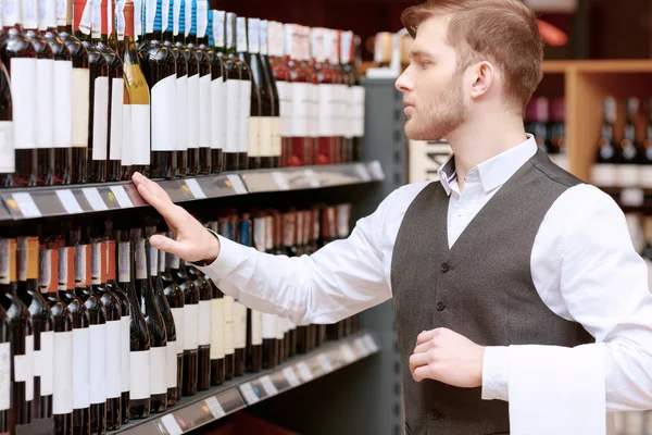 Sommelier na loja perto de prateleiras — Fotografia de Stock