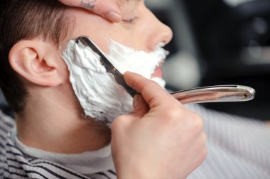 Client shaving at barber shop clipart