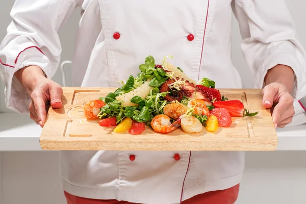 Cook holds a cutting board with salad — Stock Photo, Image
