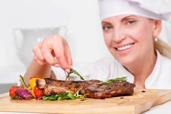 Cook   putting  rosemary on meat steak — Stock Photo, Image