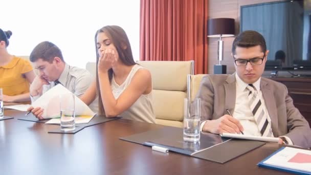 Company of young people sitting in modern light conference hall having tedious time — Stock Video